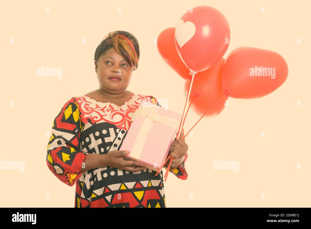 Femme africaine noire grasse réfléchie tenant un tas de ballons rouges Avec enseigne en forme de cœur prête pour la Saint-Valentin Banque D'Images