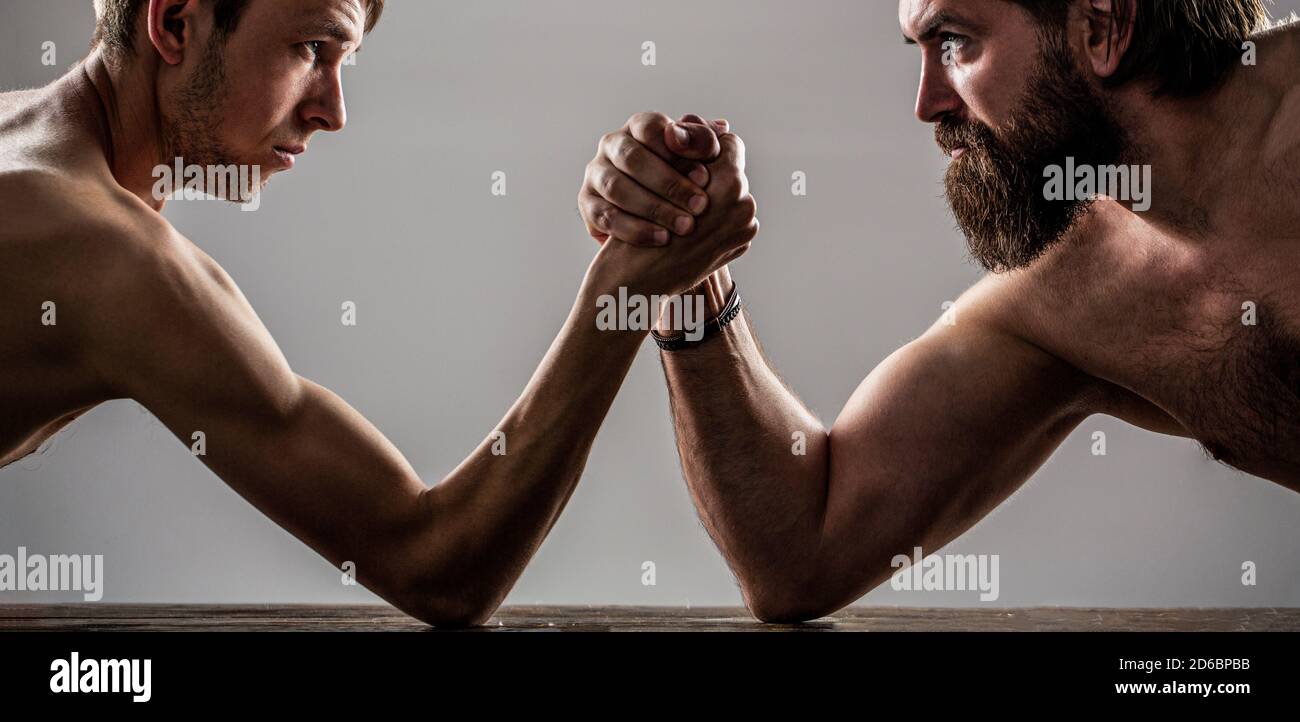 Deux mains d'homme ont un bras de lutte, forte et faible, match inégal. Homme barbu fortement musclé bras luttant un homme faible et puny Banque D'Images