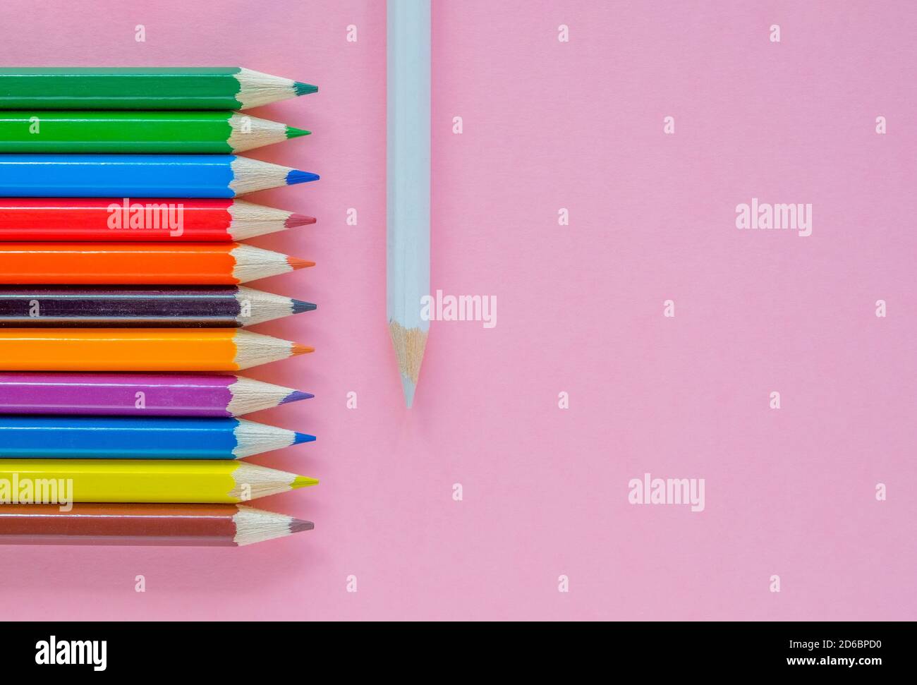 Plusieurs crayons multicolores sont disposés sur un fond rose Banque D'Images