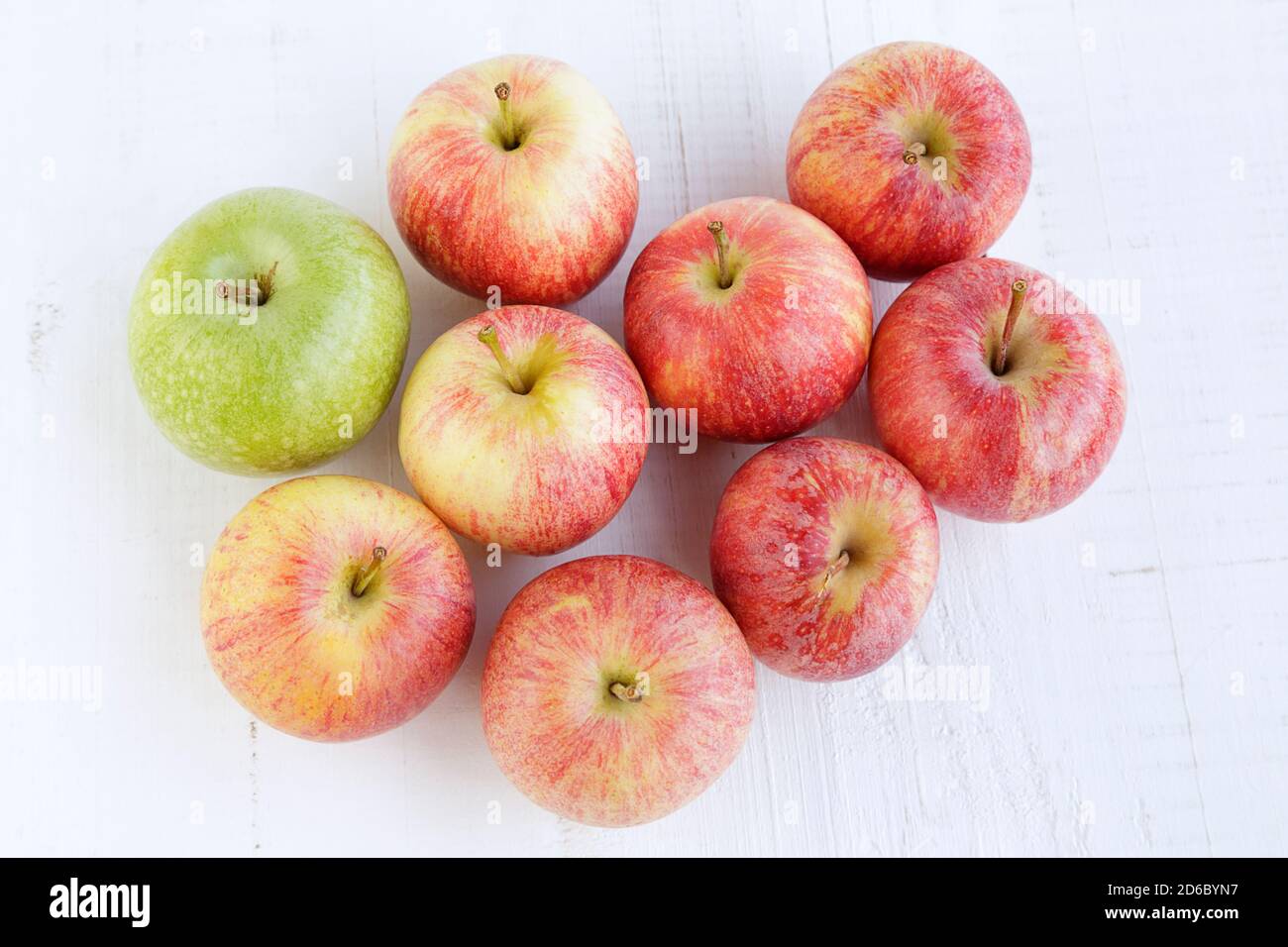 Vue de dessus de plusieurs pommes rouges et une pomme verte sur une ancienne table en bois blanc Banque D'Images