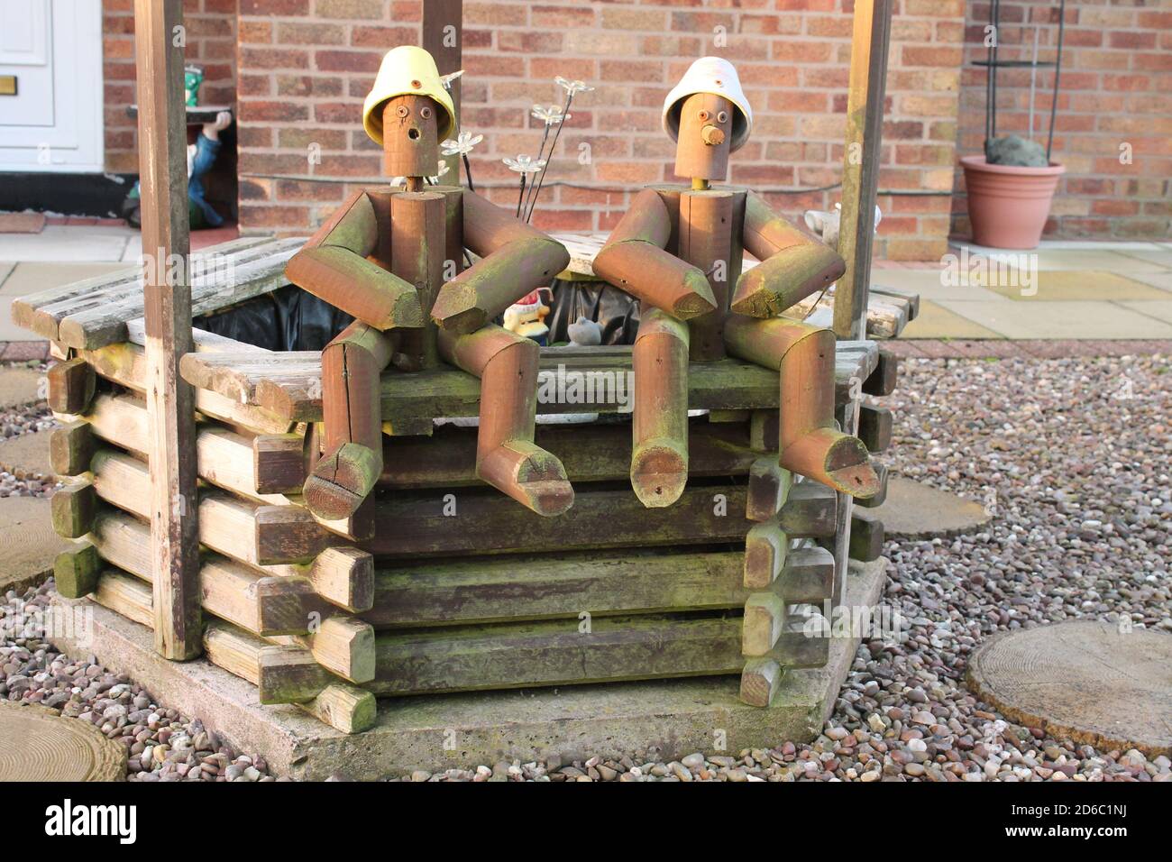 Deux hommes de pot de fleurs en bois se sont assis au-dessus d'un puits Dans un jardin à l'avant du Royaume-Uni Banque D'Images