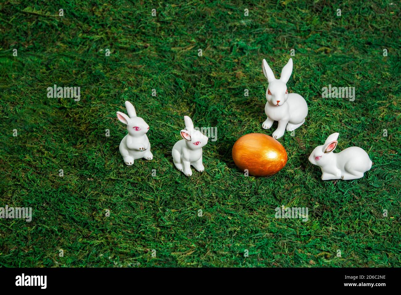 Joyeuses Pâques. Félicitations de pâques. Petits lapins blancs autour de l'oeuf doré sur un fond de mousse. Espace pour le texte. Banque D'Images