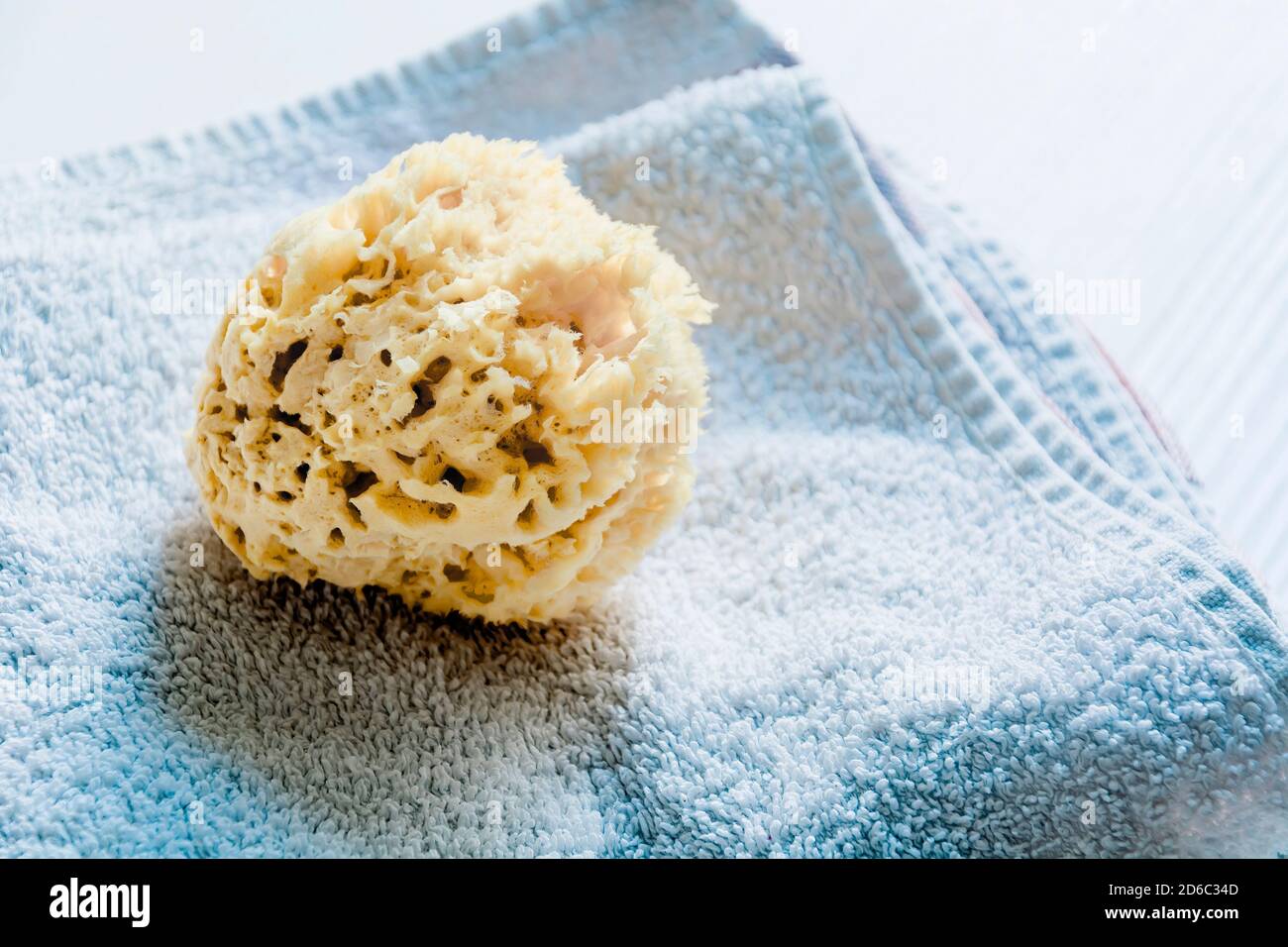 Une éponge jaune naturel sur les serviettes empilées sur une table en bois blanc. Soins personnels et hygiène. Bain et détente Banque D'Images