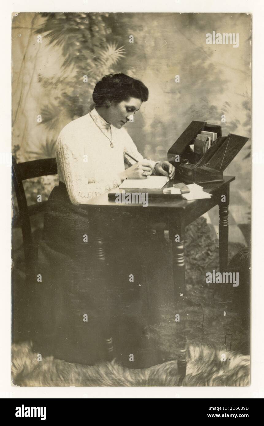 Début des années 1900 après l'époque Edwardian studio portrait carte postale de la femme attirante, appelée Trixie B. Neville, assis à un bureau, daté de Noël 1912 au dos, Royaume-Uni Banque D'Images