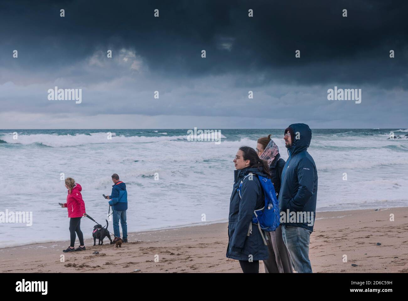 Une famille de vacanciers se tenant sur une plage de Fistral venteuse et profitant de la vue sur la baie de Fistral à Newquay, dans les Cornouailles. Banque D'Images