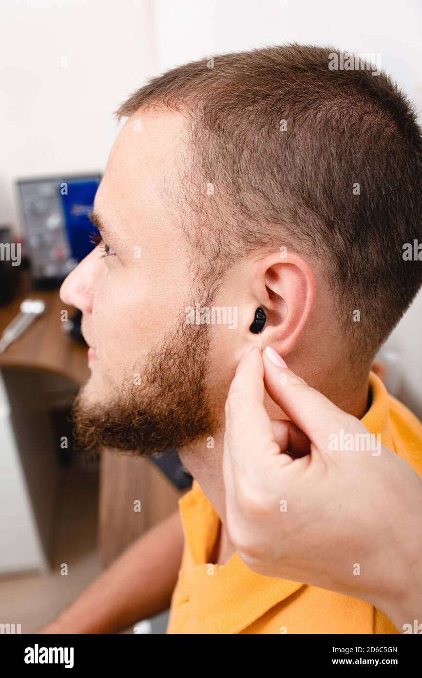 Homme patient avec prothèse auditive intra-auriculaire, gros plan à l'intérieur de l'oreille mâle. Solution auditive, audiologiste insérant une prothèse auditive sur le patient Banque D'Images