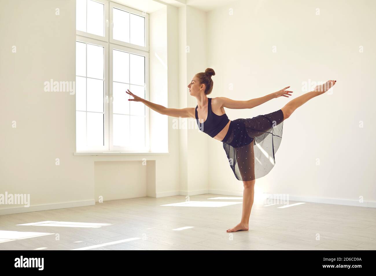 Fille debout avec la jambe étirée et pratiquant le ballet classique ou danse moderne en studio Banque D'Images