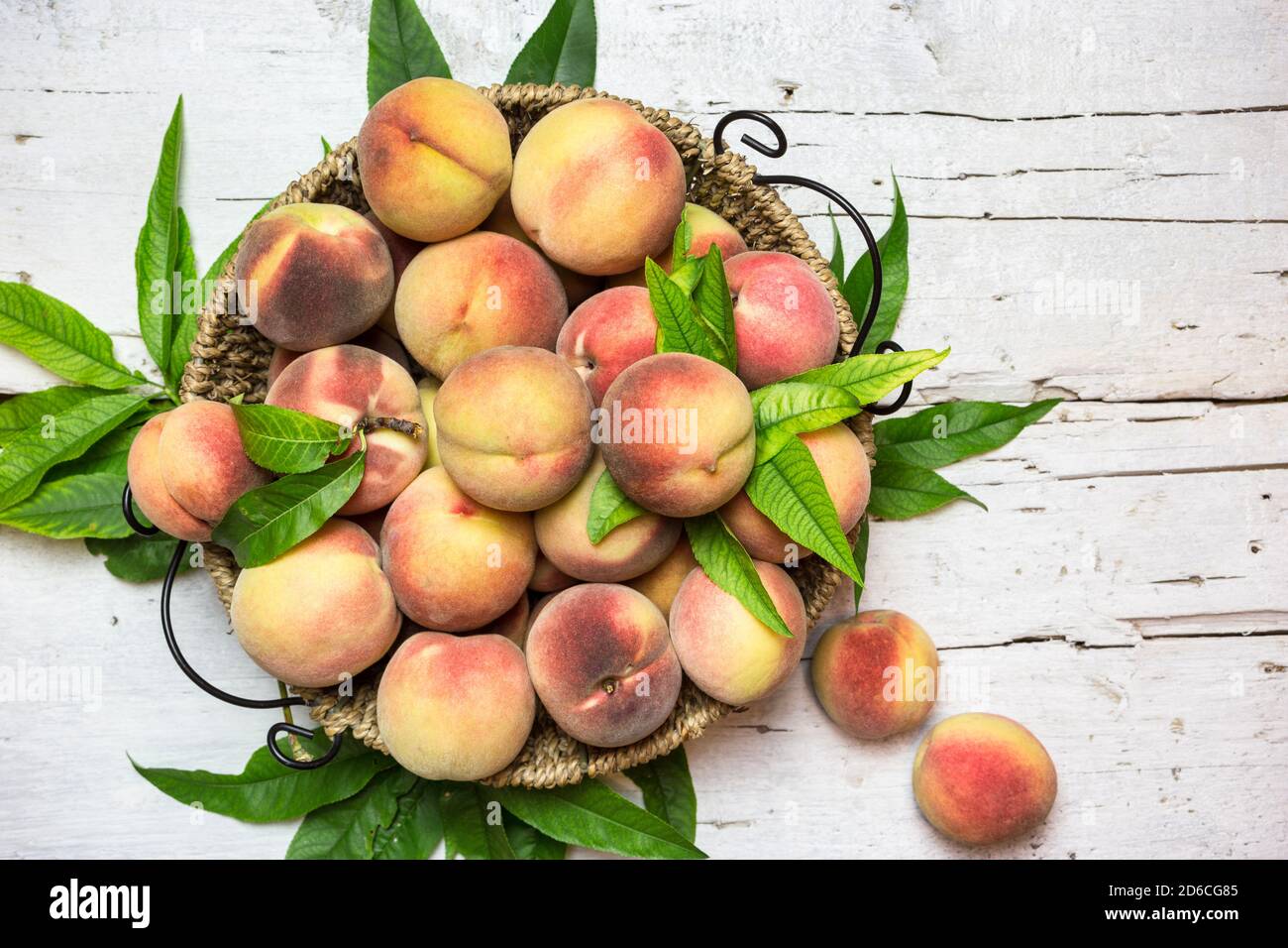Pêches rouges mûres dans un panier sur une table blanche rustique, vue du dessus. Fruits biologiques sains. Banque D'Images