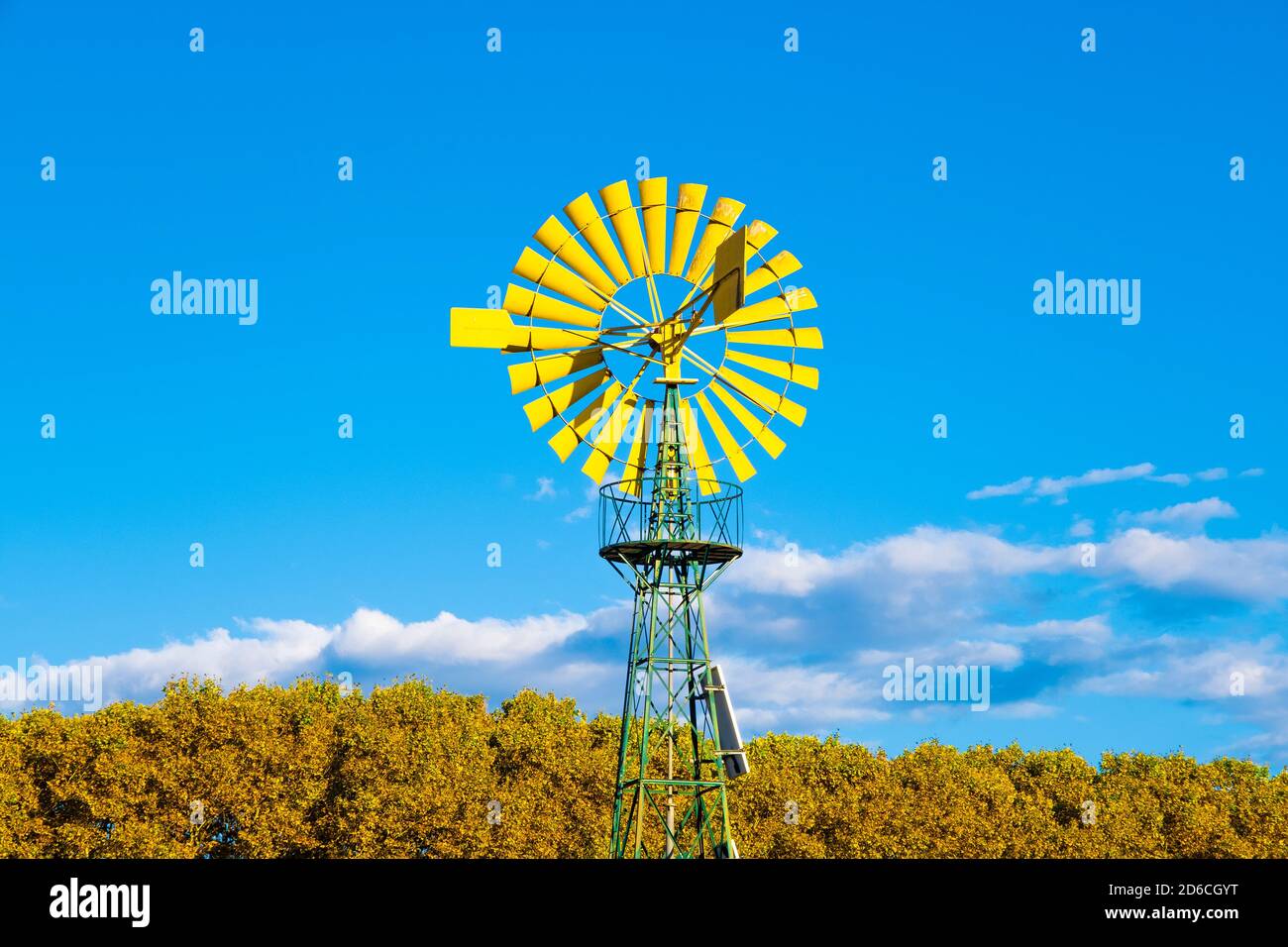 Moulin à vent jaune contre un ciel bleu dans une ferme. Concept d'énergie renouvelable avec espace de copie vide pour le contenu de l'éditeur. Banque D'Images
