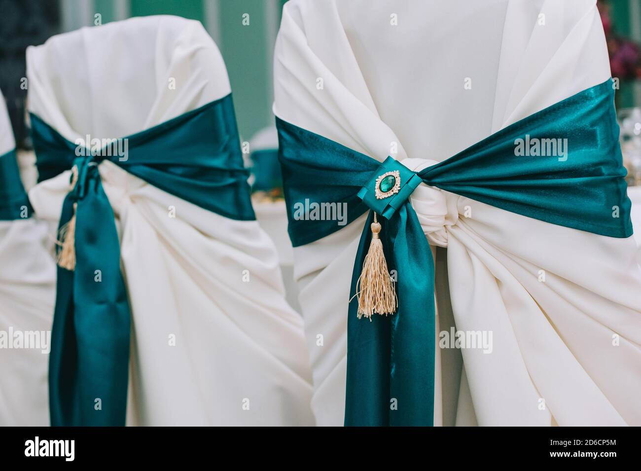 Rangée de magnifiques chaises décorées de tissus et d'arcs de couleur verte dans la salle de mariage. Banque D'Images