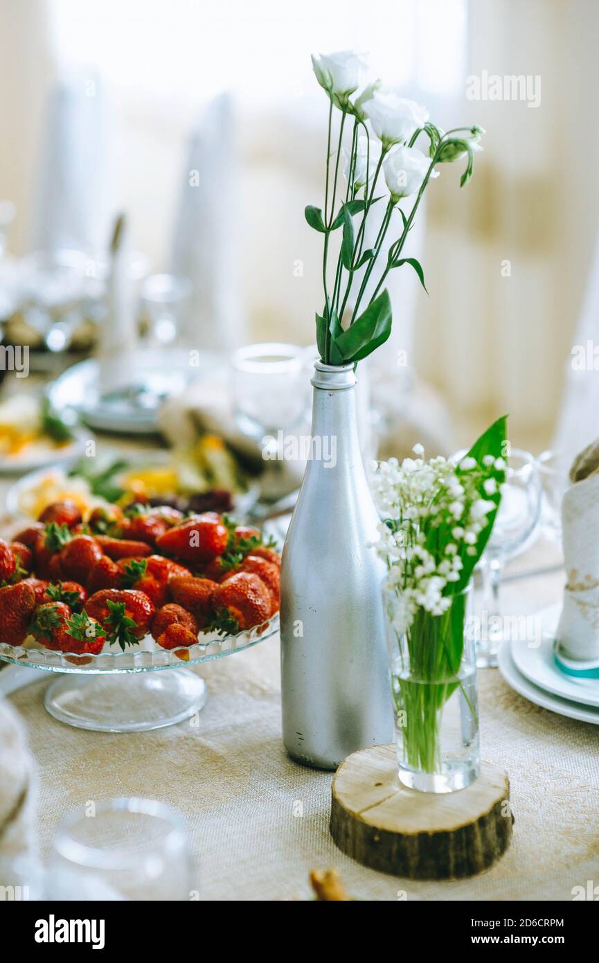 Gros plan de l'euphorie blanche et du nénuphars de la vallée dans des vases en verre sur une table de fête. Banque D'Images