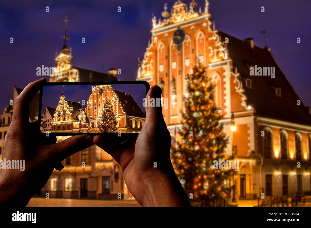 Touriste prenant la photo de l'arbre de Noël à Riga. Maison des Blackheads avec arbre de Noël la nuit, vieille ville de Riga, Lettonie Banque D'Images