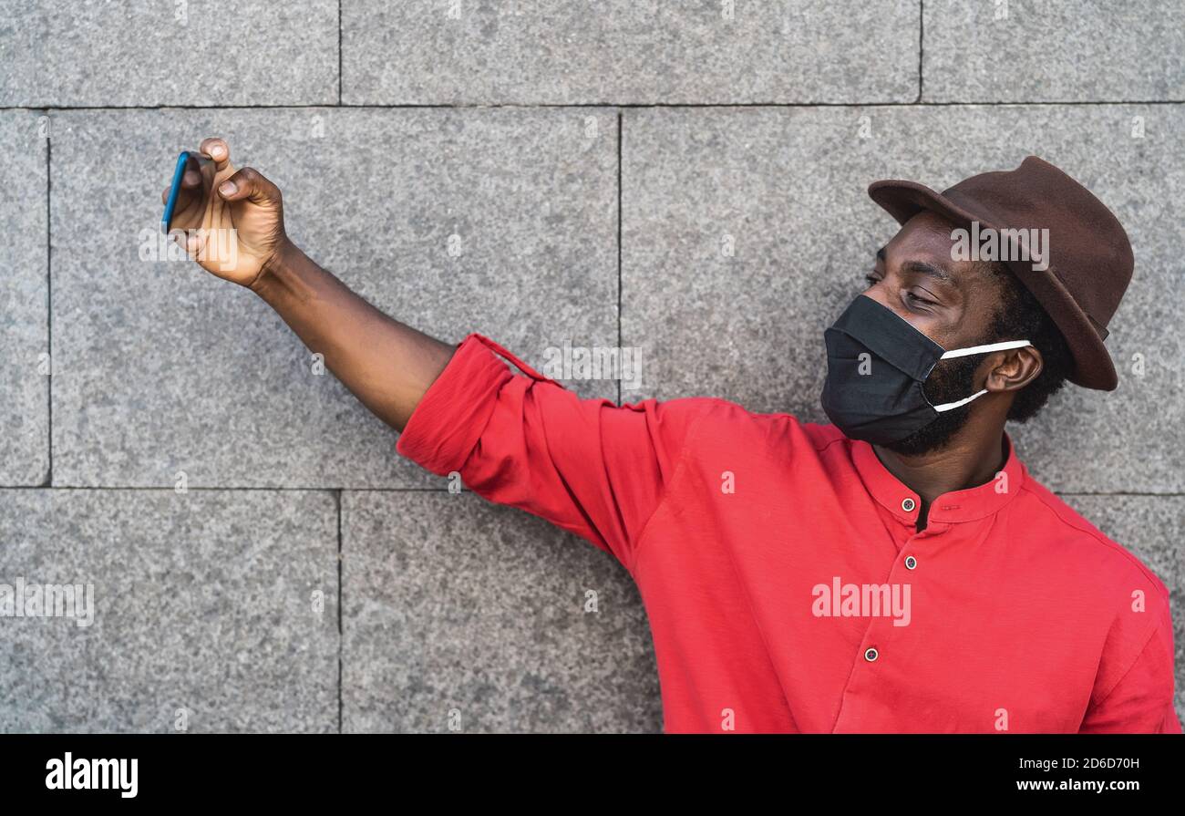 Homme de mode africain prenant le selfie avec un smartphone et portant le visage Masque noir pour éviter la propagation du virus corona - santé des personnes concept de soins et de technologie Banque D'Images