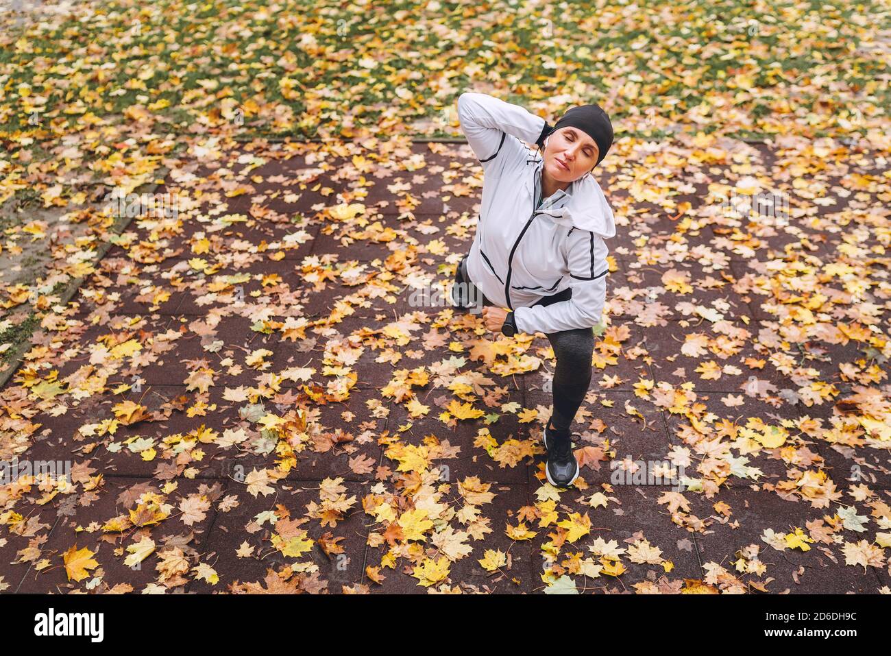 Faites de l'exercice à une femme athlétique avant de faire du jogging dans le parc municipal d'automne sur l'aire de jeux pour enfants. Jeune femme de fitness s'étirant les jambes pendant que wa Banque D'Images