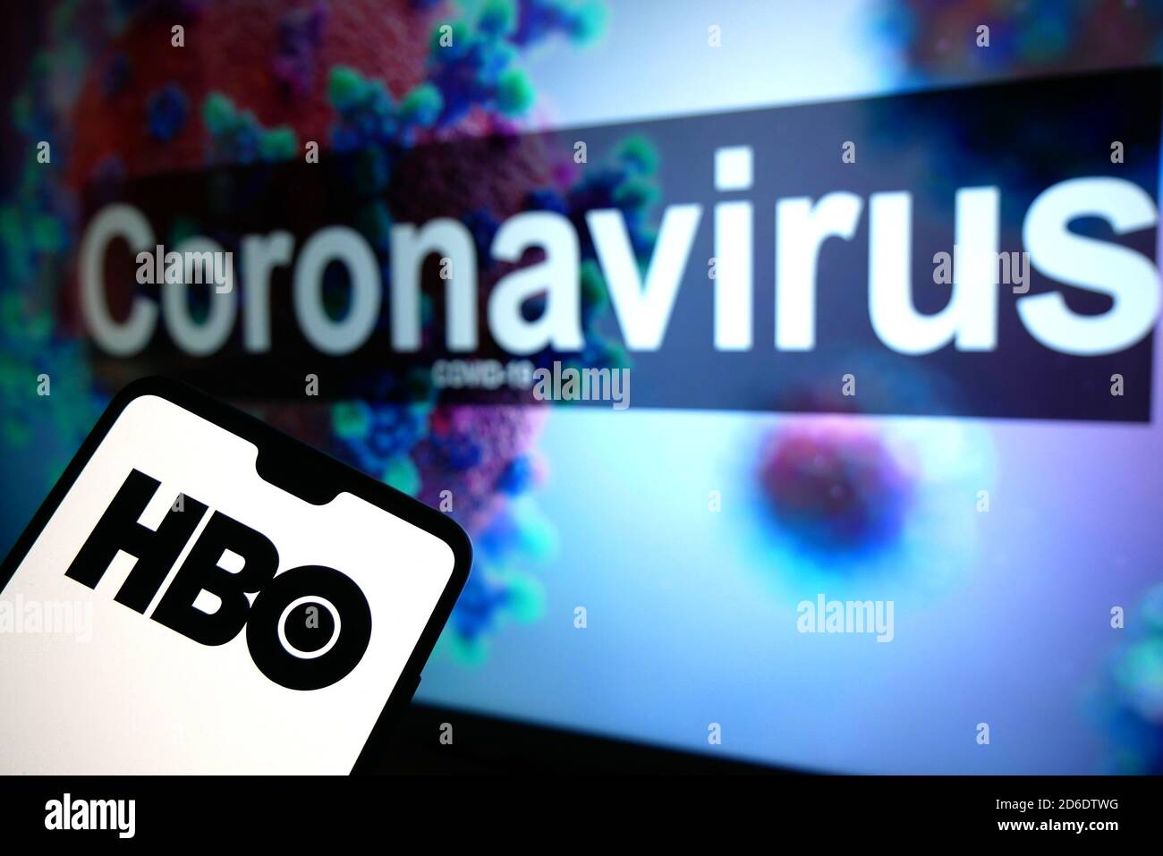 Le logo HBO affiché sur un téléphone mobile avec un modèle d'illustration du coronavirus affiché sur un moniteur en arrière-plan. Banque D'Images