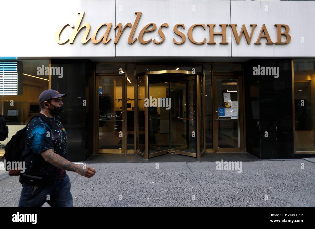 Un homme portant un masque passe devant un bureau de vente Charles Schwab près de Grand Central terminal. Banque D'Images