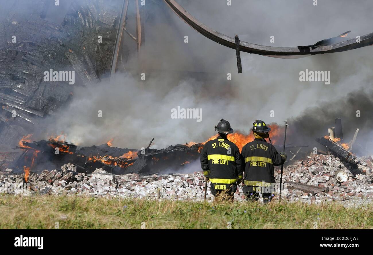 St. Louis, États-Unis. 16 octobre 2020. Deux pompiers de Saint-Louis ne peuvent regarder les restes d'un toit et d'acier torsadé que lors d'un incendie de trois alarmes à Saint-Louis le vendredi 16 octobre 2020. Les rafales de vent atteignant 30 miles par heure ont contribué à pousser les flammes dans tout le bloc long de l'entrepôt. Photo par Bill Greenblatt/UPI crédit: UPI/Alay Live News Banque D'Images