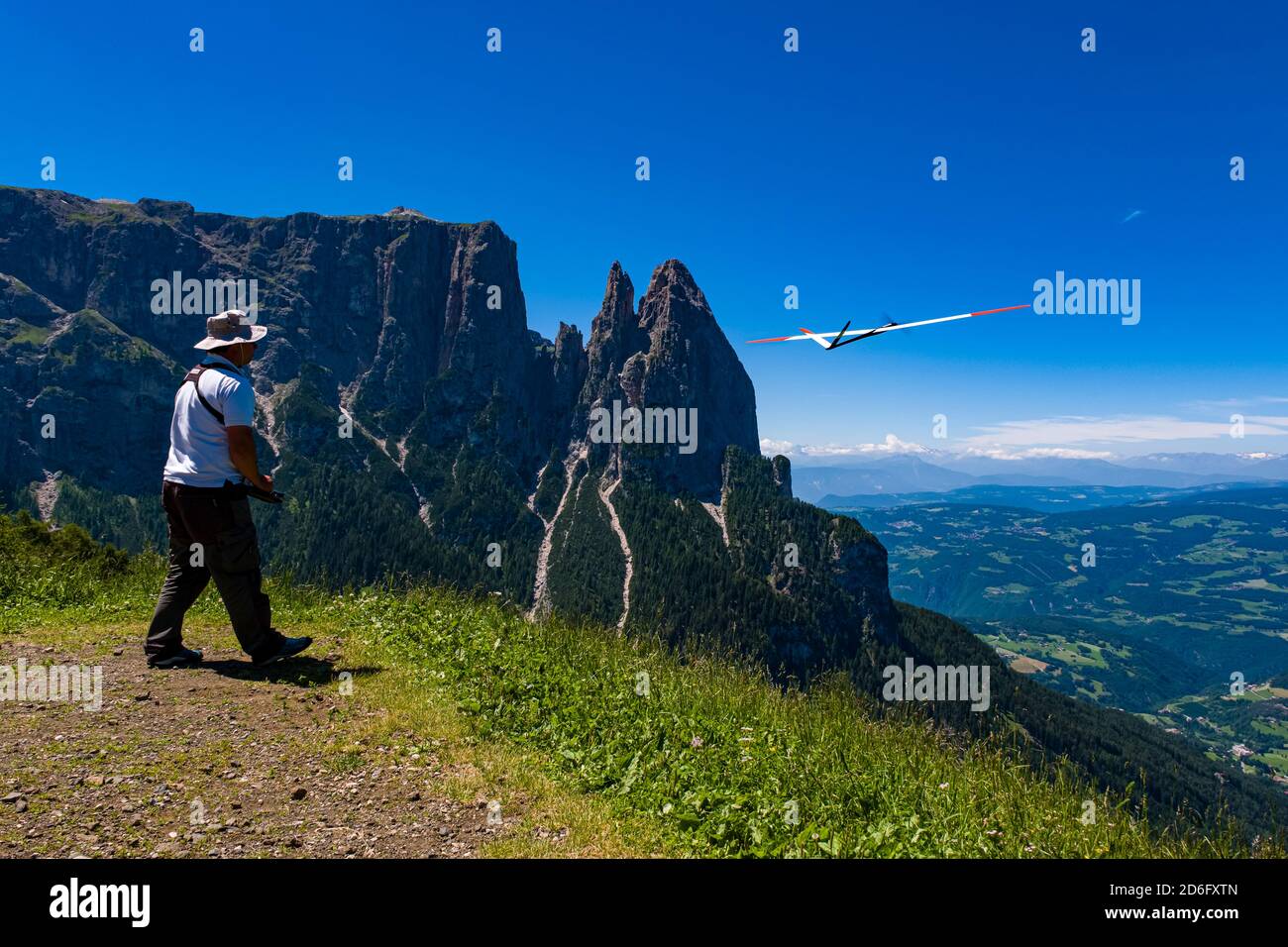 Un homme commence un avion modèle à Seiser Alm, Alpe di Siusi, la montagne Schlern, Sciliar, au loin. Banque D'Images