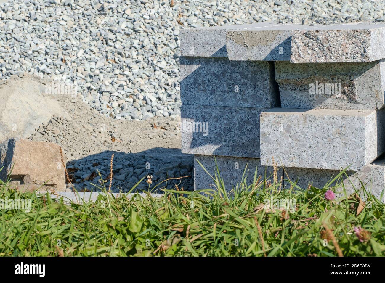 Travaux de construction. Plaques de granit artificielles préparées pour l'installation d'une bordure sur le fond d'une pile de gravier. Mise au point sélective. Banque D'Images