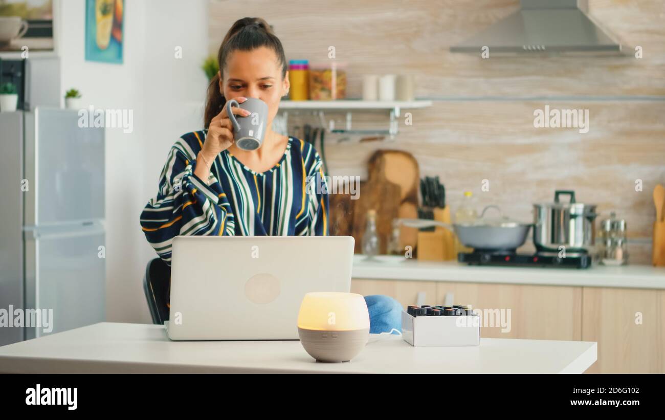 Boire du café et travailler avec le diffuseur d'huiles essentielles  d'aromathérapie dans la cuisine. Arôme santé essence, welness aromathérapie  maison spa parfum apaisante thérapie, vapeur thérapeutique, traitement de  santé mentale Photo Stock -