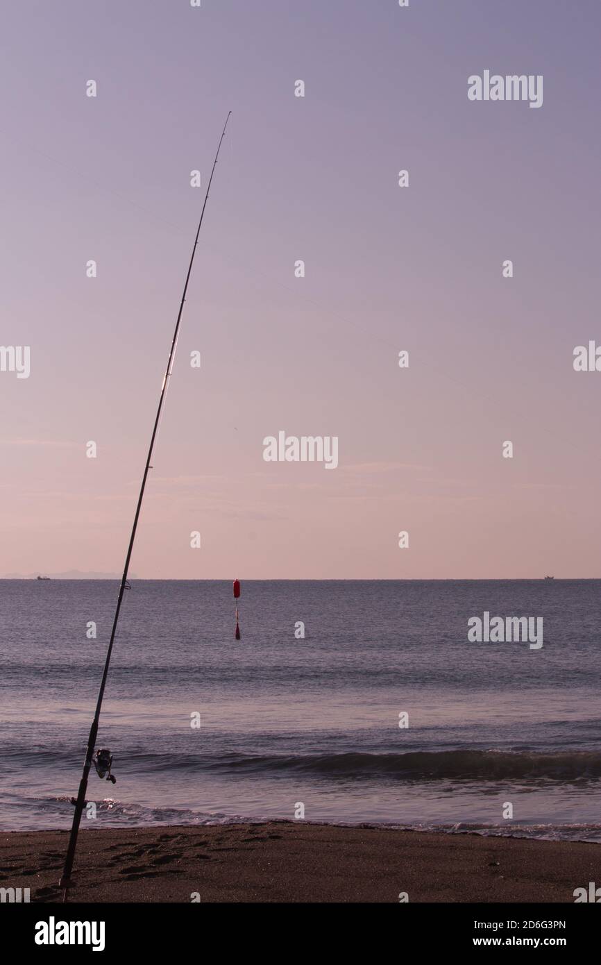 Silhouette de canne à pêche et de lure sur la plage à l'aube Banque D'Images
