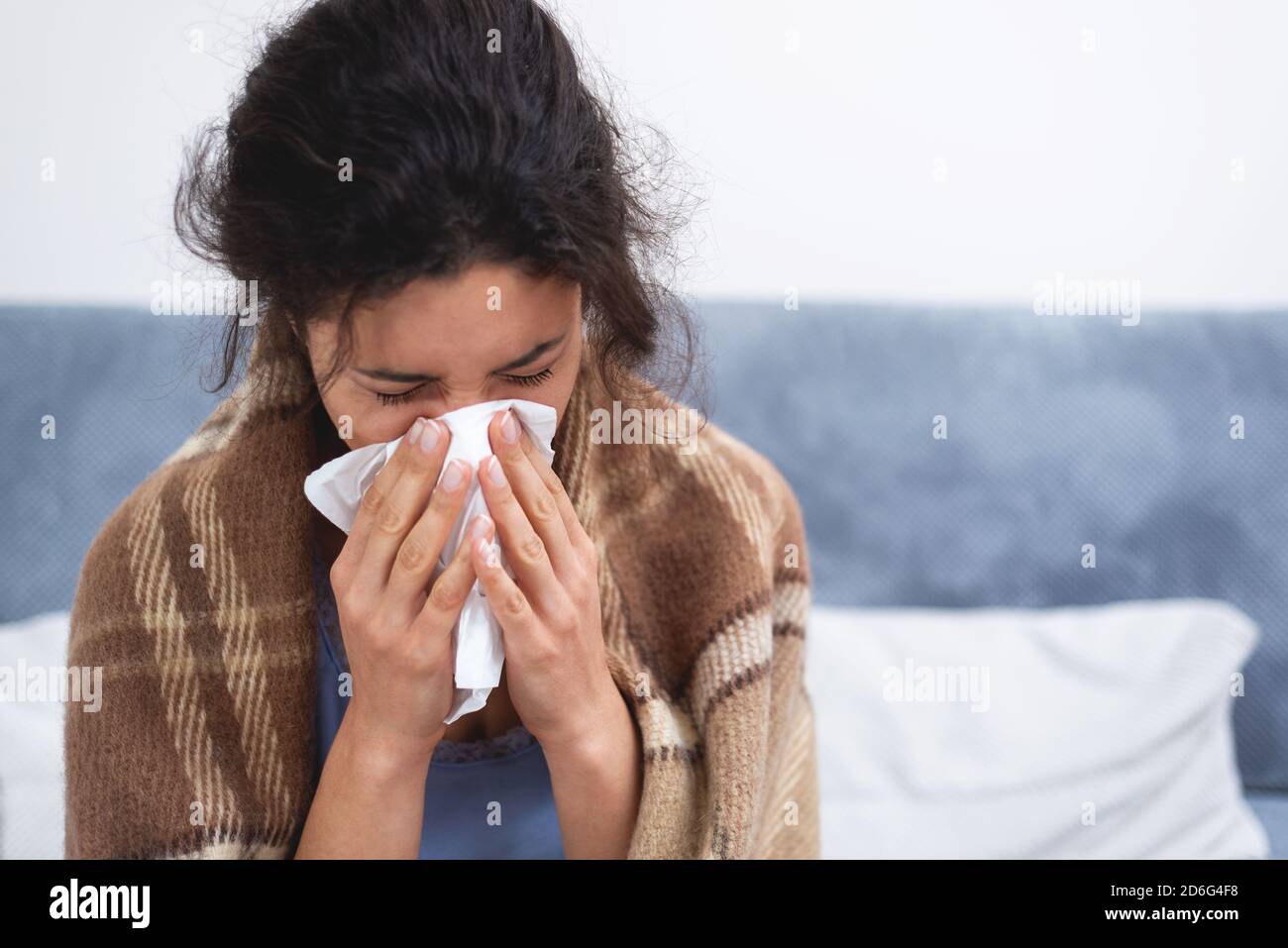 Portrait de la jeune femme à la maison avec une infection virale. La femme souffle son nez dans un mouchoir en papier. Pandémie, sur l'auto-isolement. Banque D'Images