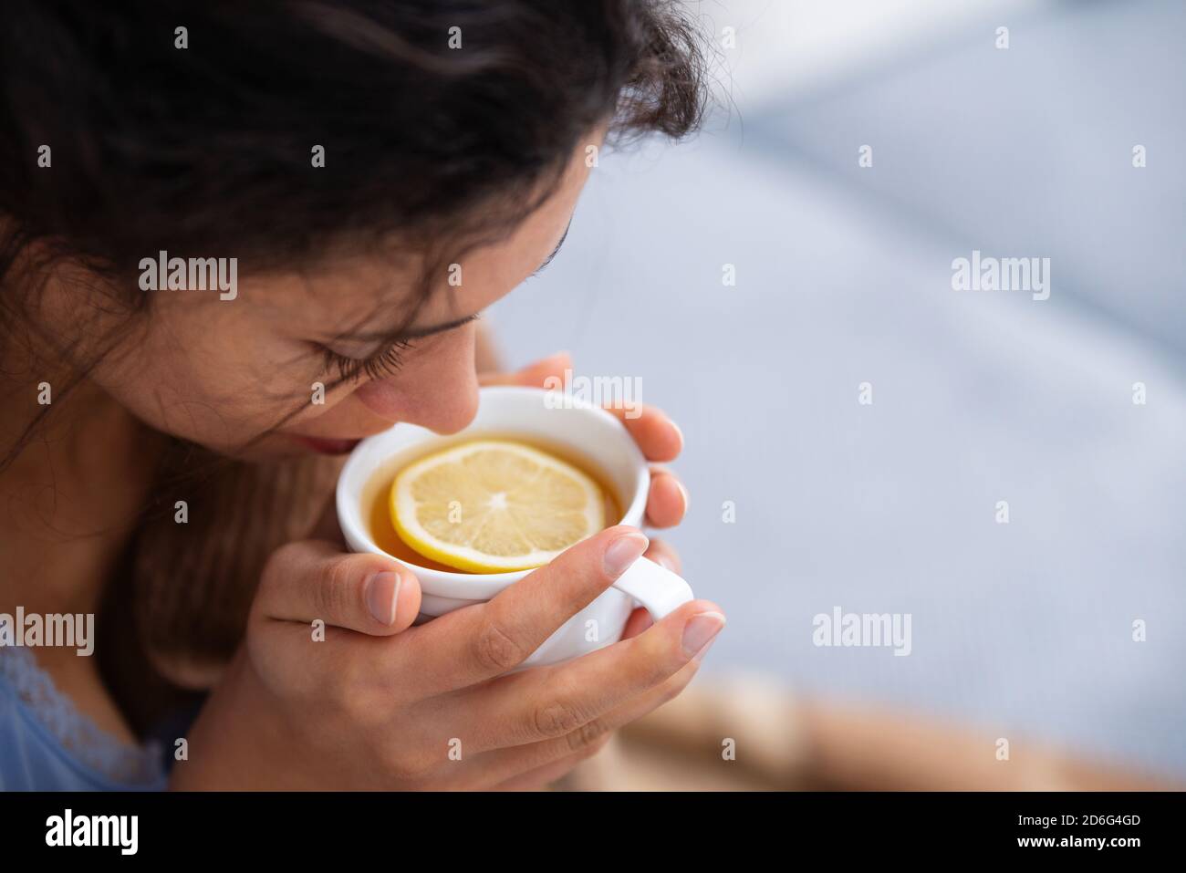 Gros plan de la jeune femme à la maison avec une infection virale. La femme boit du thé chaud avec du citron. Pandémie, sur l'auto-isolement. Banque D'Images