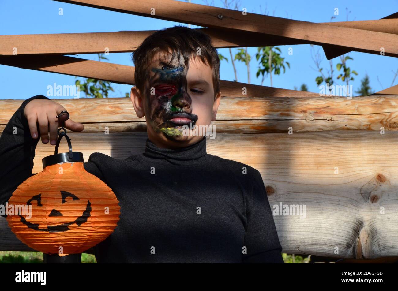 garçon avec maquillage noir pour halloween, zombie. Effrayant petit garçon souriant portant le maquillage de crâne pour halloween halloween citrouille lanterne, bonbons Banque D'Images