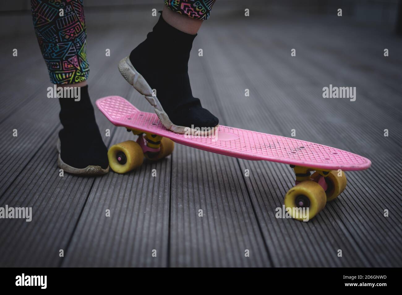 gros plan sur le pied de la jeune fille dans une foulée noire sur le skate-board rose penny Banque D'Images