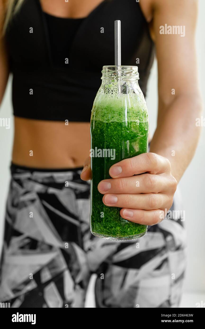 Femme sportive tenant une bouteille de smoothie de Detox vert. Concept de régime alcalin Banque D'Images