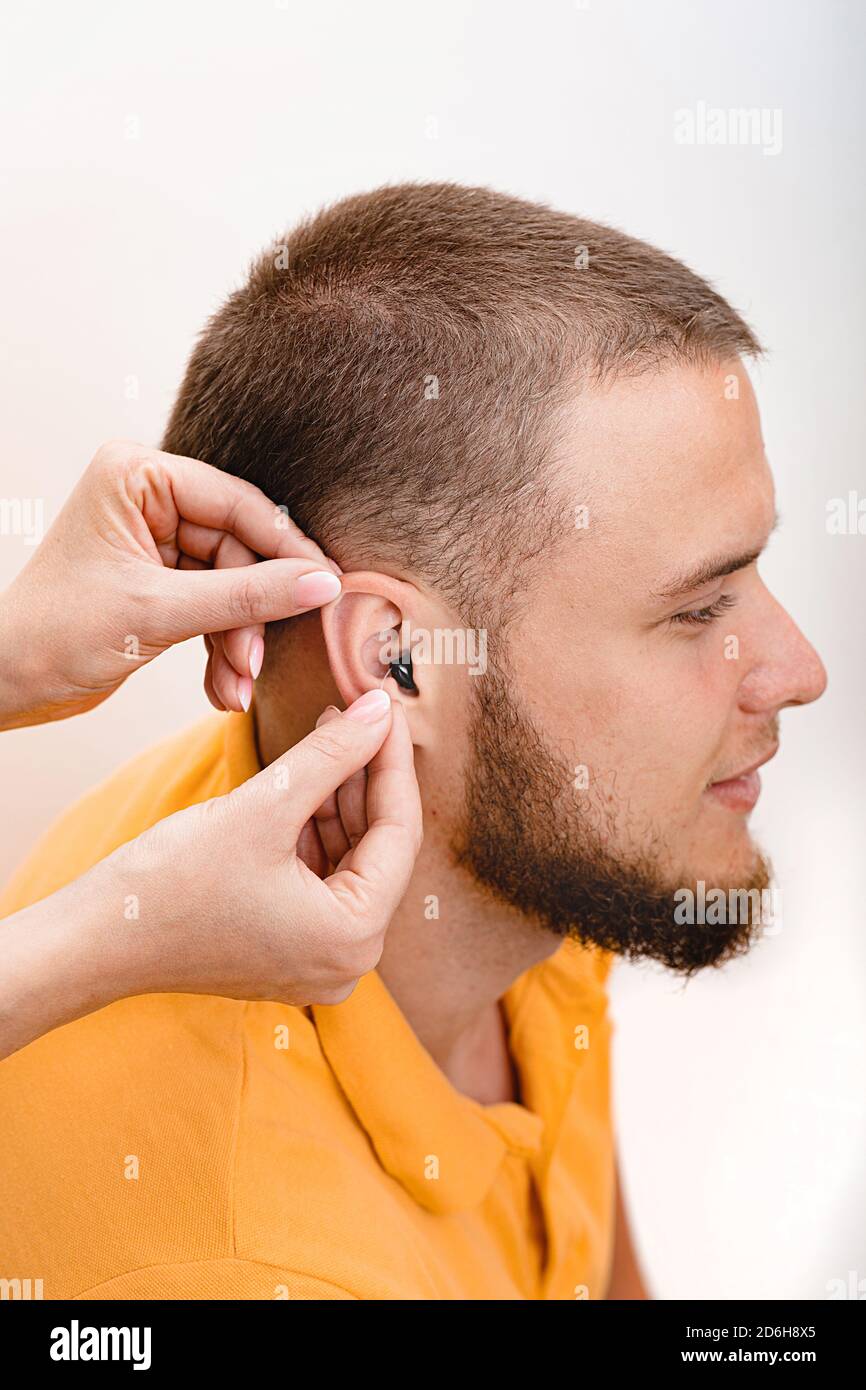 Homme patient avec prothèse auditive intra-auriculaire, gros plan à l'intérieur de l'oreille mâle. Solution auditive, audiologiste insérant une prothèse auditive sur le patient Banque D'Images