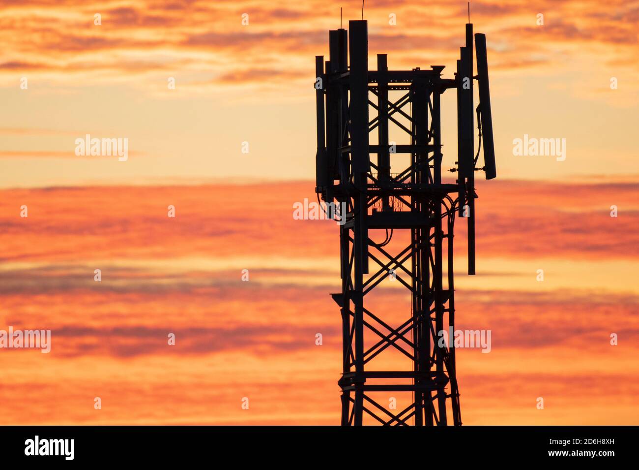 Une tour de téléphone mobile contre un ciel orangé au coucher du soleil à Cardiff, pays de Galles, Royaume-Uni. Banque D'Images