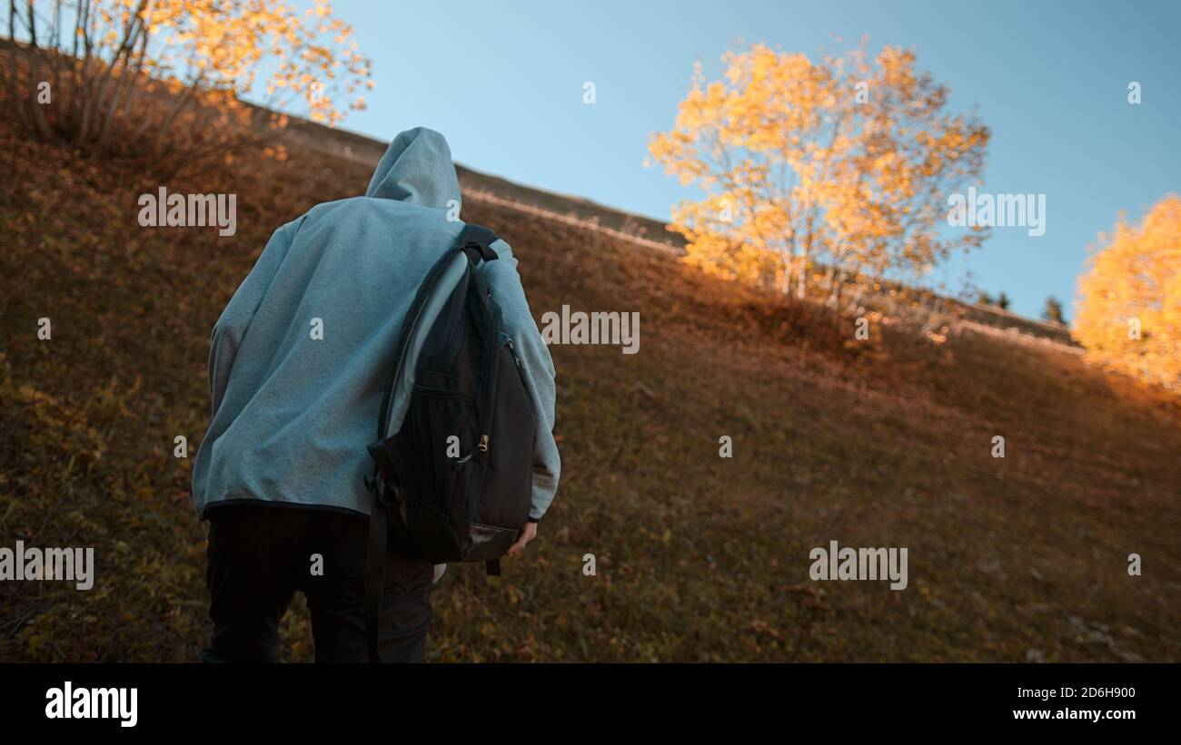 Hippie grimpeur avec son sac à dos derrière lui grimper une pente raide dans la forêt, la nature et le concept de style de vie Banque D'Images