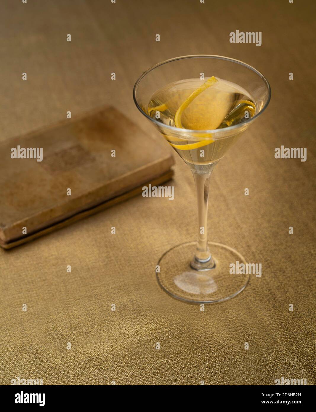 Cocktail de vodka Martini avec twist citron sur tissu doré avec vieux livre Banque D'Images