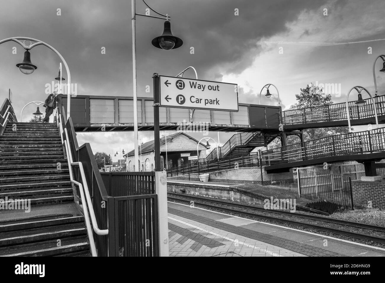 Homme appuyé contre un pont en acier à une gare urbaine locale. Banque D'Images