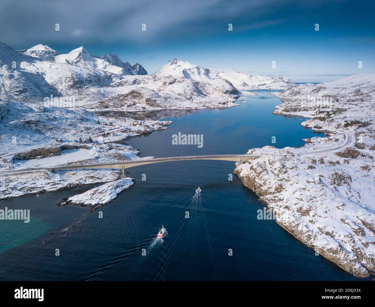 Vue aérienne, fjord seaway avec montagnes enneigées, pont avec route et petits bateaux de pêche, Nordland, Lofoten, Norvège Banque D'Images