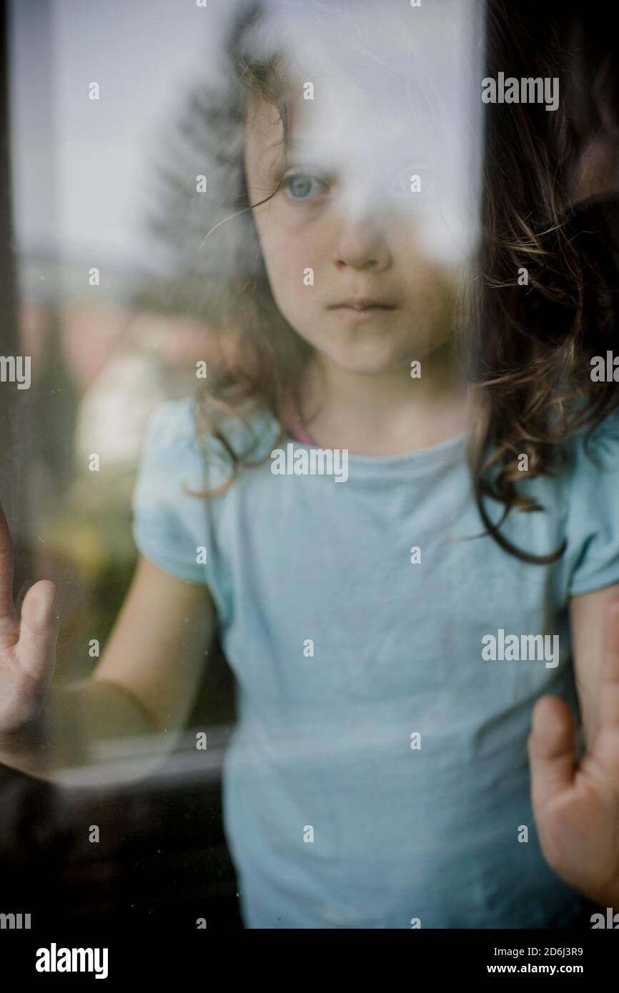 L'enfant regarde malheureusement à travers le volet de fenêtre Banque D'Images