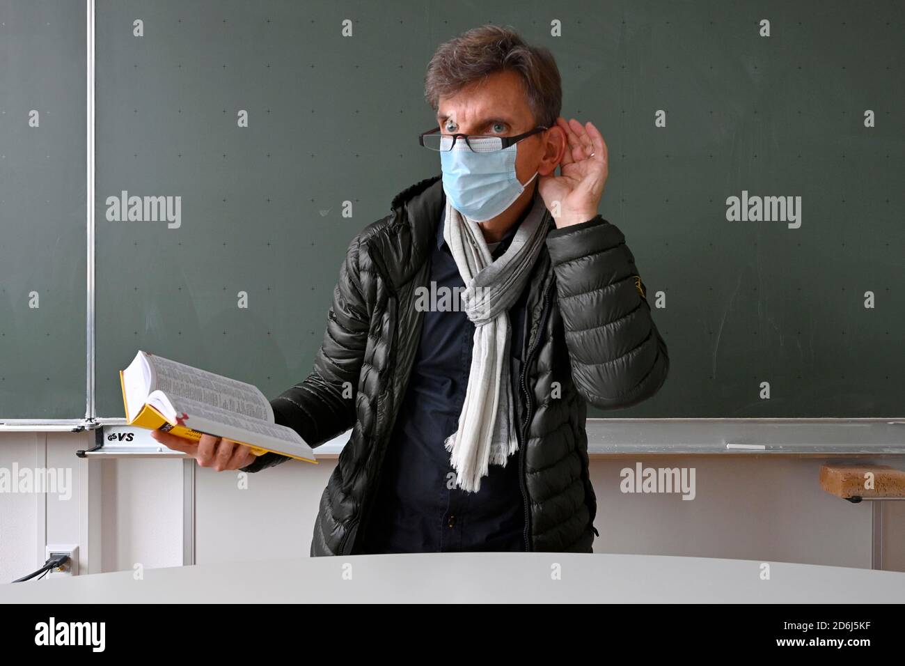 Professeur avec une veste d'hiver épaisse, foulard et masque facial en classe, main sur l'oreille, problèmes de communication, crise corona, Stuttgart, Baden-Wuerttemberg Banque D'Images