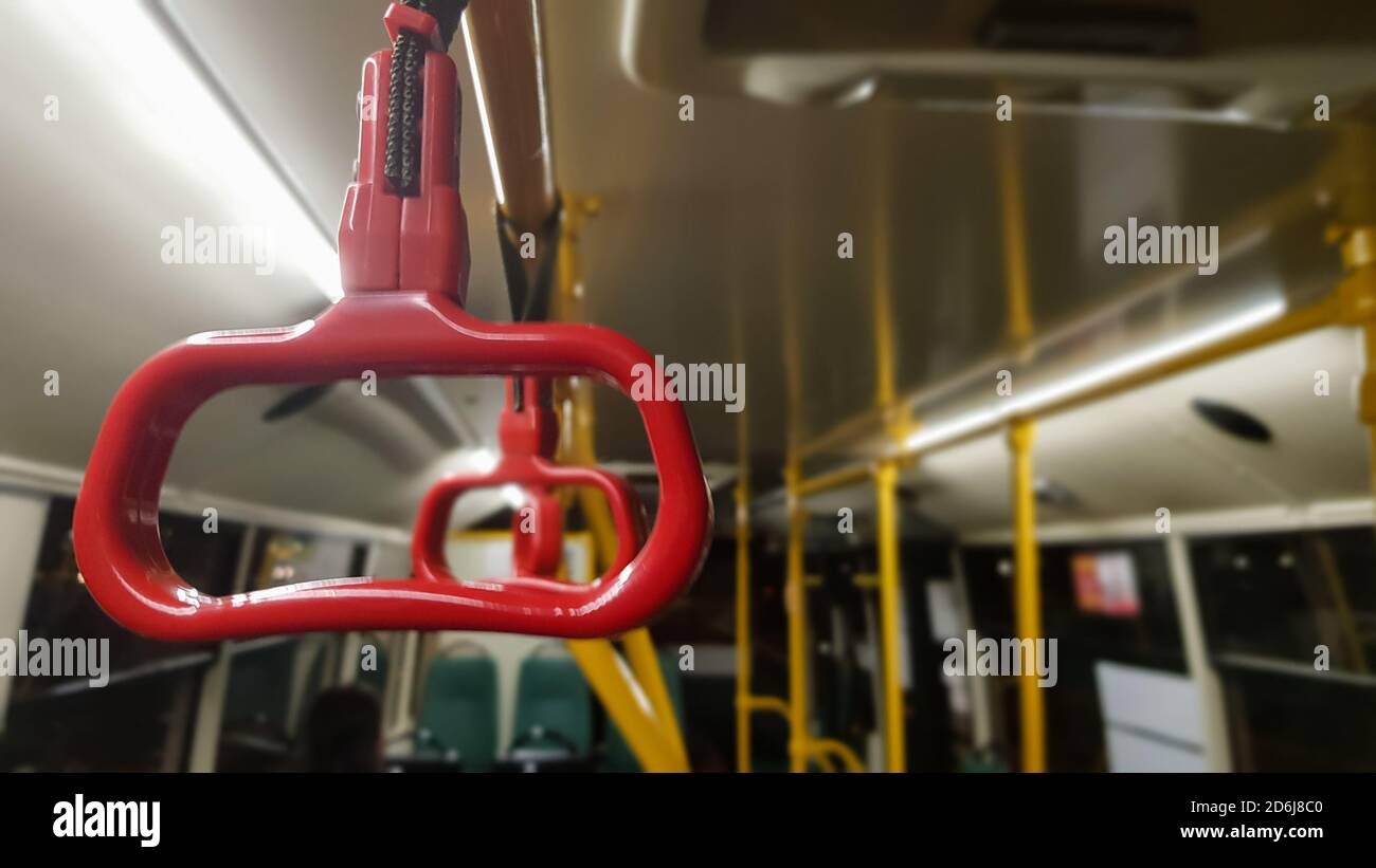 Main courante suspendue rouge au plafond pour les passagers debout pendant le transport. Transports publics urbains et suburbains modernes. Bus vide Banque D'Images