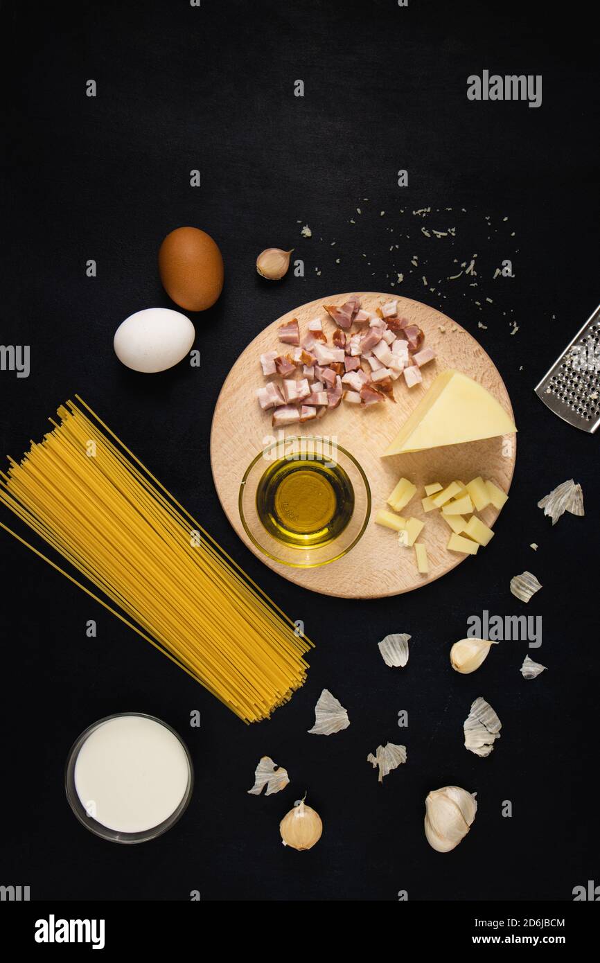 Pâtes italiennes traditionnelles ingrédients Carbonara : bacon, spaghetti, parmesan, fromage, œufs, ail, crème et huile d'olive. Vue de dessus, plat. Banque D'Images