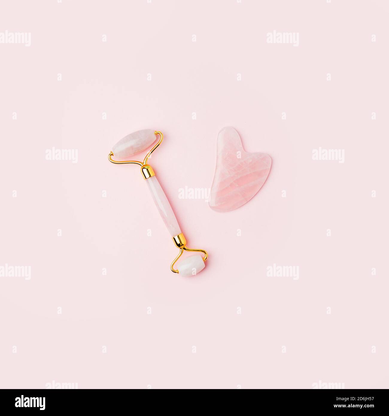 Outils de massage du visage Pink Gua Sha. Rouleau de jade à quartz rose et pierre sur fond rose. Traitement anti-âge, levage et tonification à la maison. Copier l'espace Banque D'Images