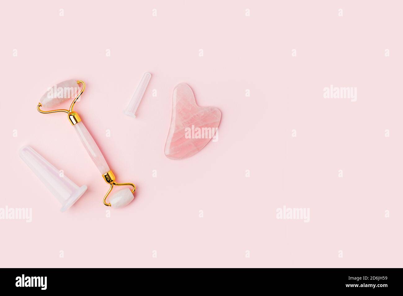 Pink Gua Sha Stone, outils de massage facial à roulettes. Rouleau de jade à quartz rose et pierre sur fond rose. Traitement anti-âge, levage et tonification à la maison. Banque D'Images