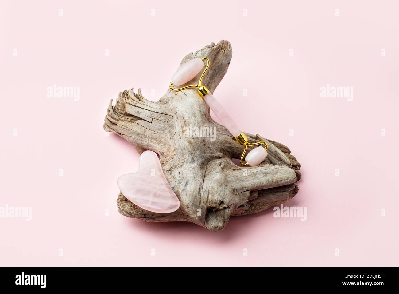 Rouleau de Jade pour le massage du visage. Outils de massage facial Pink gua sha sur racine en bois. Traitement anti-âge, levage et tonification, salon de beauté monochrome, copie Banque D'Images