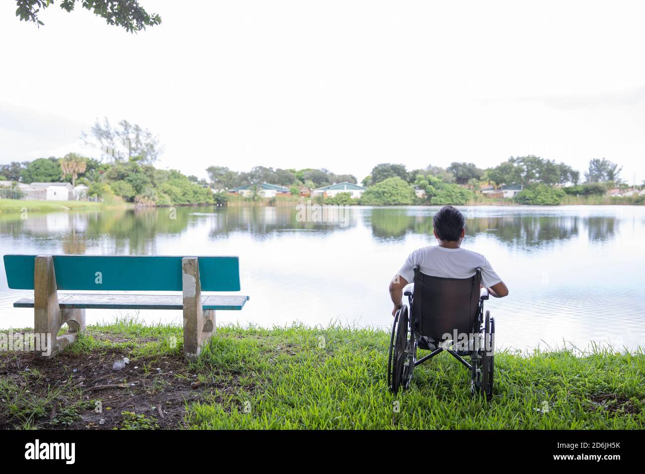 jeune homme en fauteuil roulant devant un lac Banque D'Images