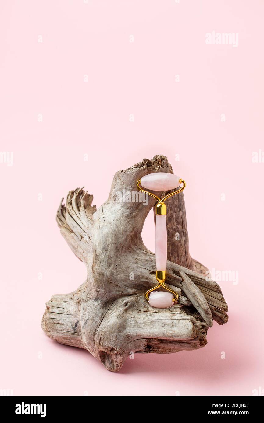Rouleau de Jade pour le massage du visage. Outils de massage facial Pink gua sha sur racine en bois. Traitement anti-âge, levage et tonification, salon de beauté monochrome, copie Banque D'Images