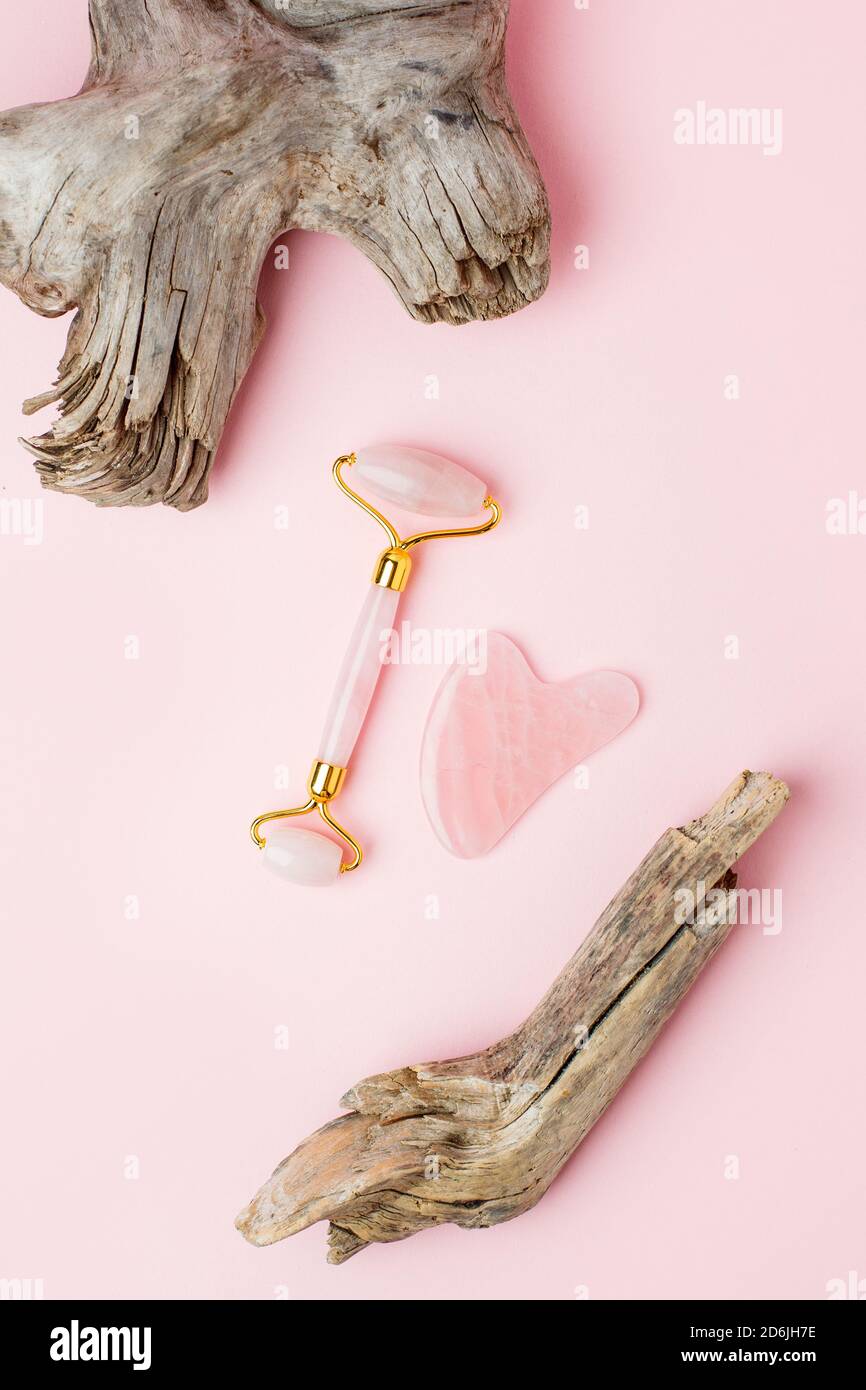 Kit de massage du visage. Rouleau de visage et masseur gua sha en pierres roses naturelles, bien-être, concept de fitness face, carte monochrome élégante, luxe b Banque D'Images