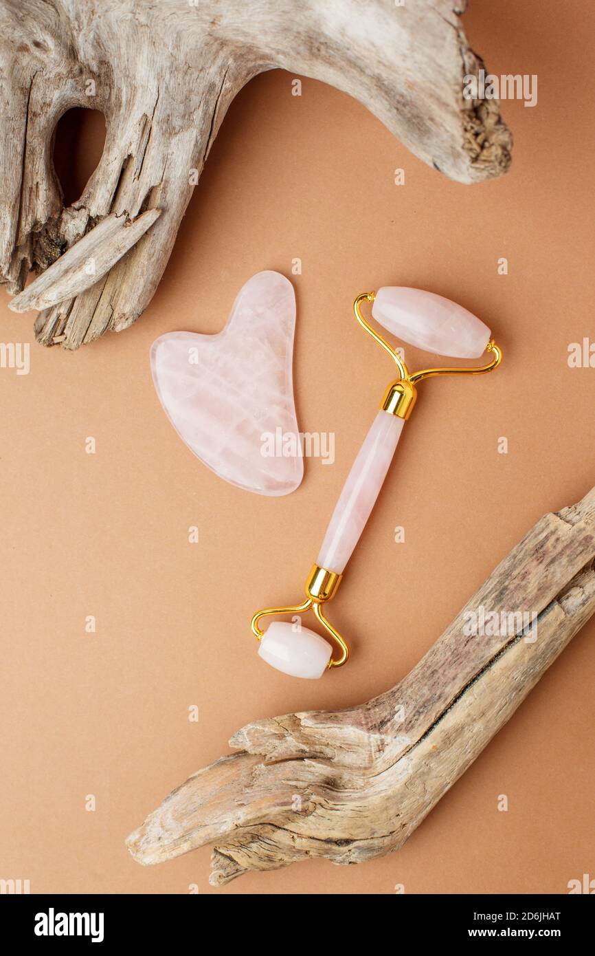 Concept de beauté moderne et luxueux - Kit de massage facial et racine en bois sur fond de papier beige. Massette à roulettes et à gua sha en natura Banque D'Images