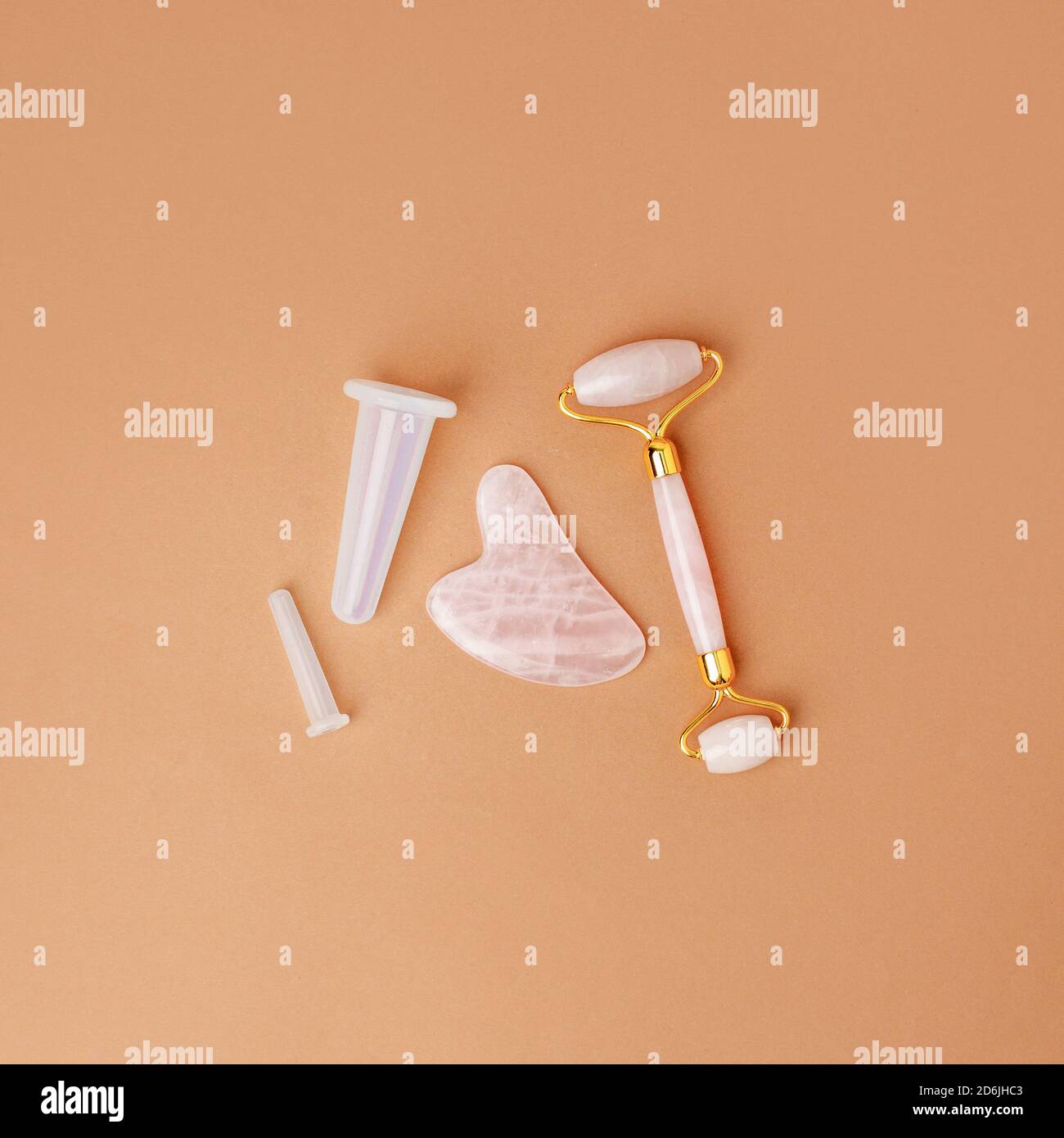 Rouleau de jade en quartz rose et pierre à outils SHA gua sur fond beige moderne. Outil de beauté tendance. Composition minimale, espace de copie, beauté blogger vie s. Banque D'Images