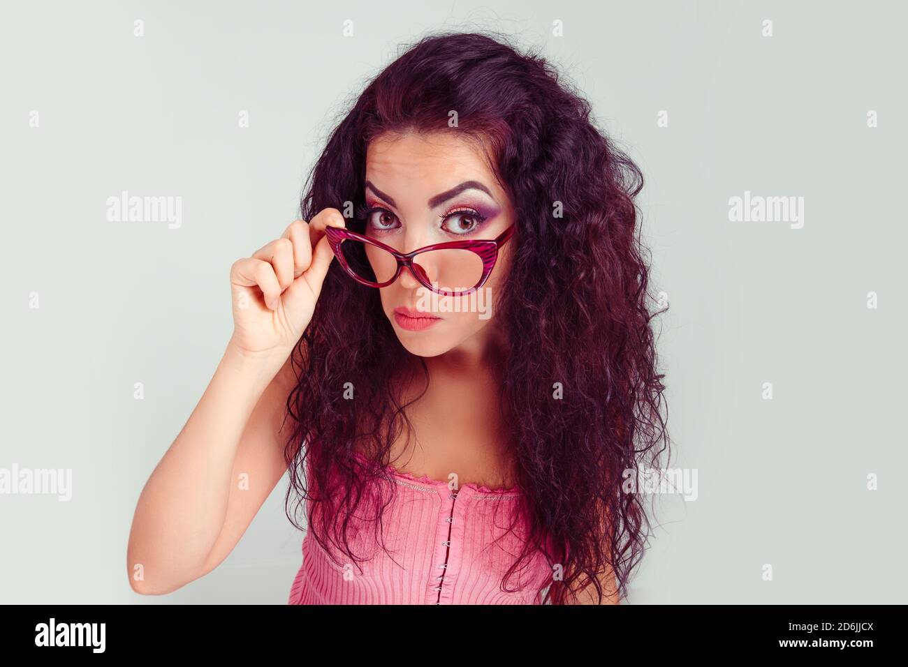 Tête de feu grave en colère bitchy femme tenant des lunettes de soleil bas en regardant avec scepticisme vous isolé vert clair gris blanc mur arrière-plan. Fac humain Banque D'Images