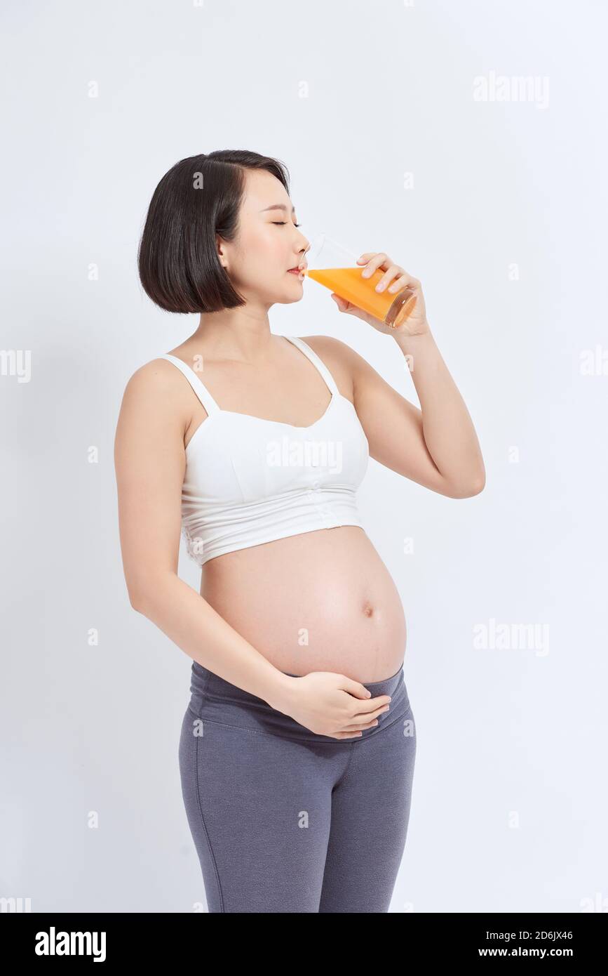 Charmante femme enceinte tenant un verre de jus d'orange tandis que l'article Banque D'Images